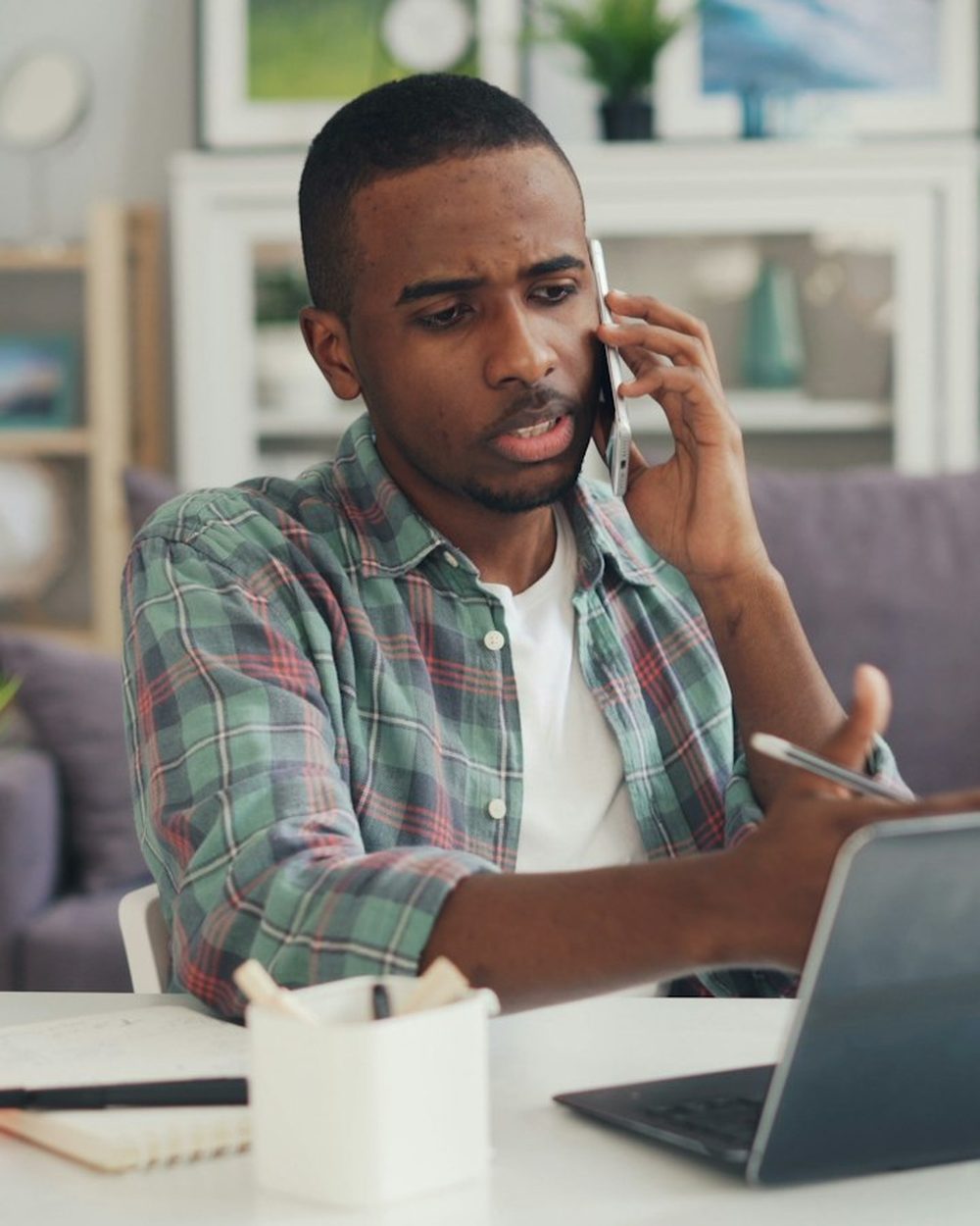 A man on a phone call at his desk at home