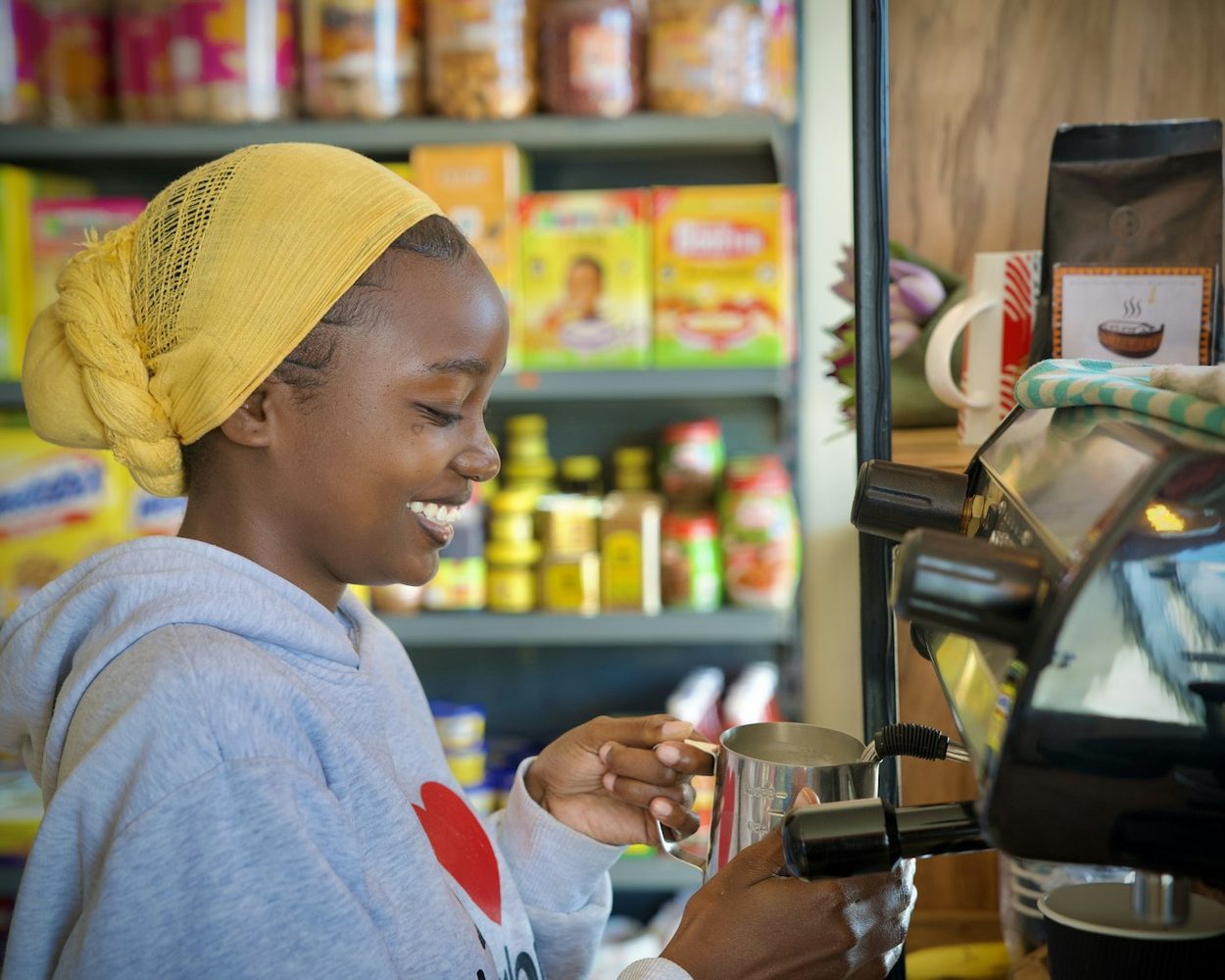 A young shopkeeper smiling as she takes a payment at her counter